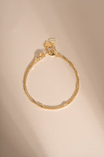 Gold box chain and satellite bracelets arranged together on a cream background.