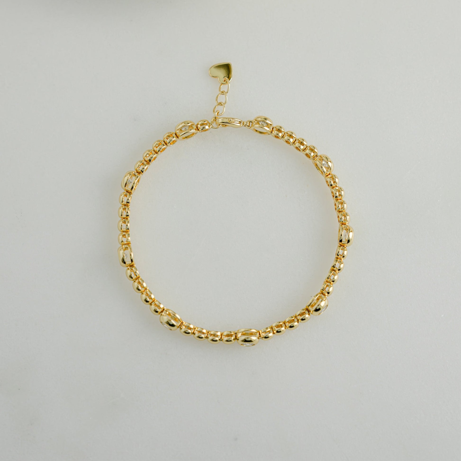 Close-up of a 14k gold tennis bracelet with alternating large and small bezels