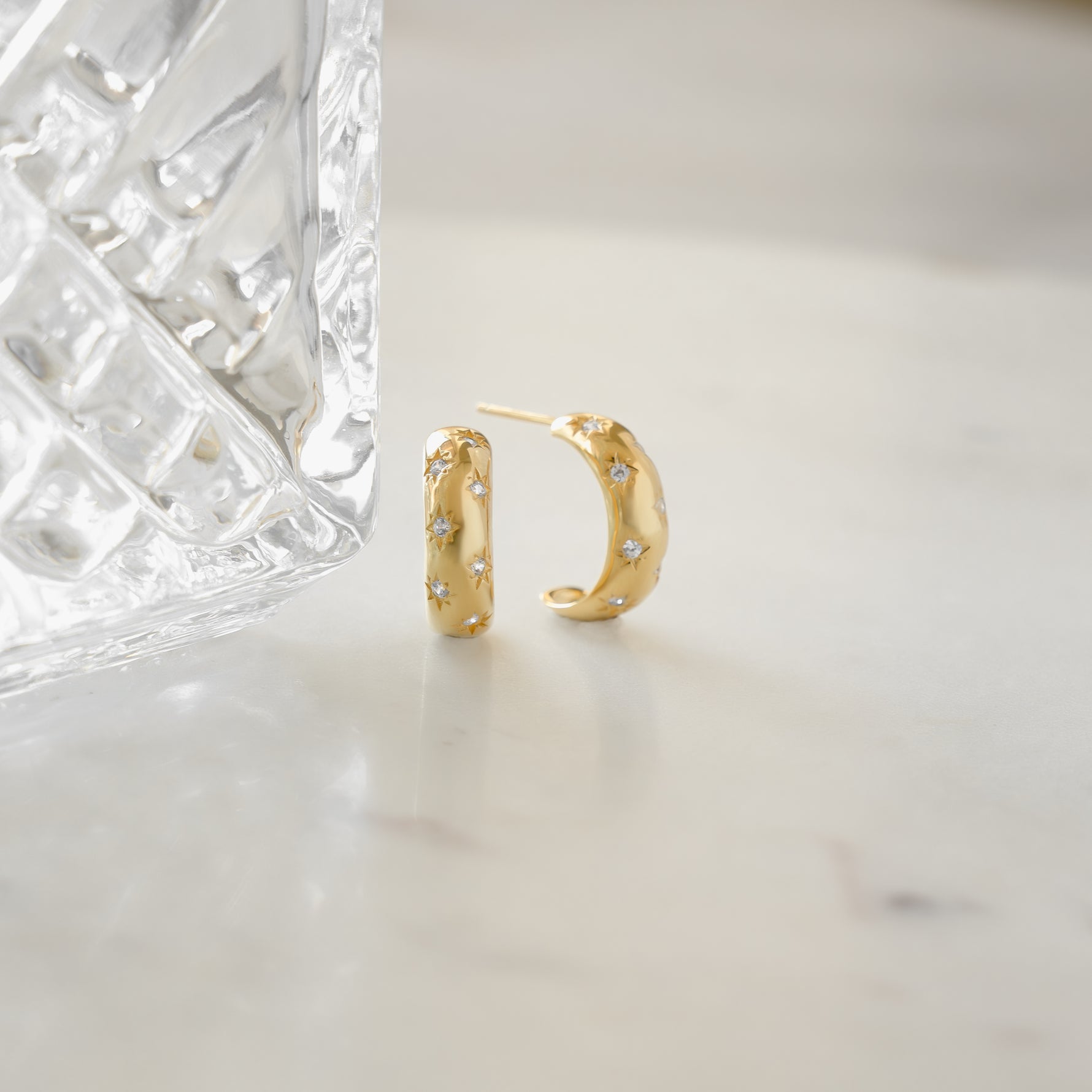 gold hoop earrings with an aesthetic design. The earrings are small hoops are celestial hoop earring design.