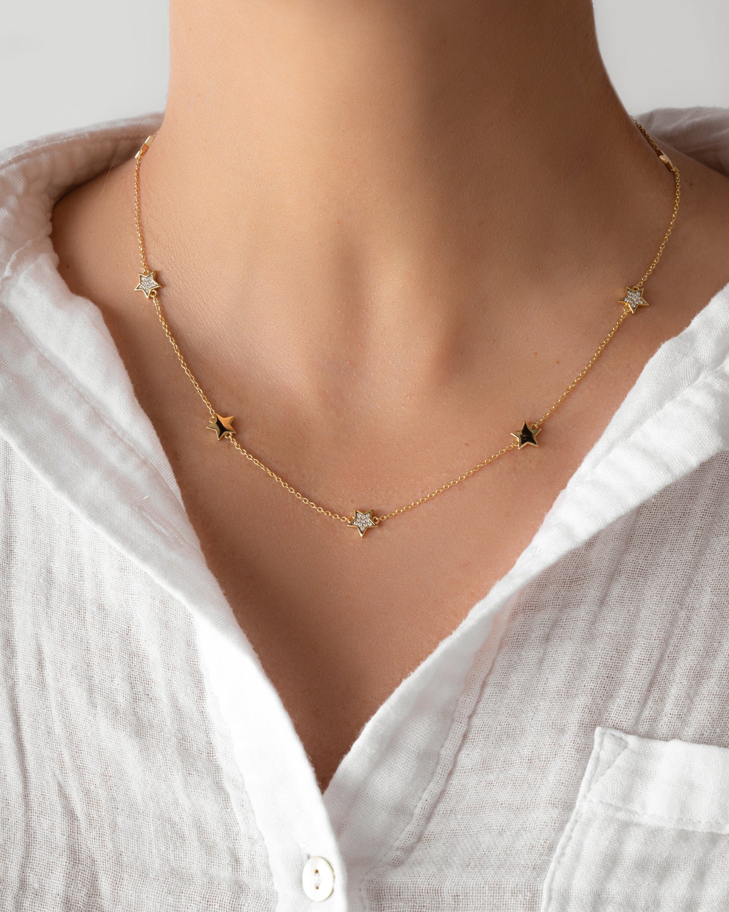 Model wearing gold charm necklace with cubic zirconia diamonds 