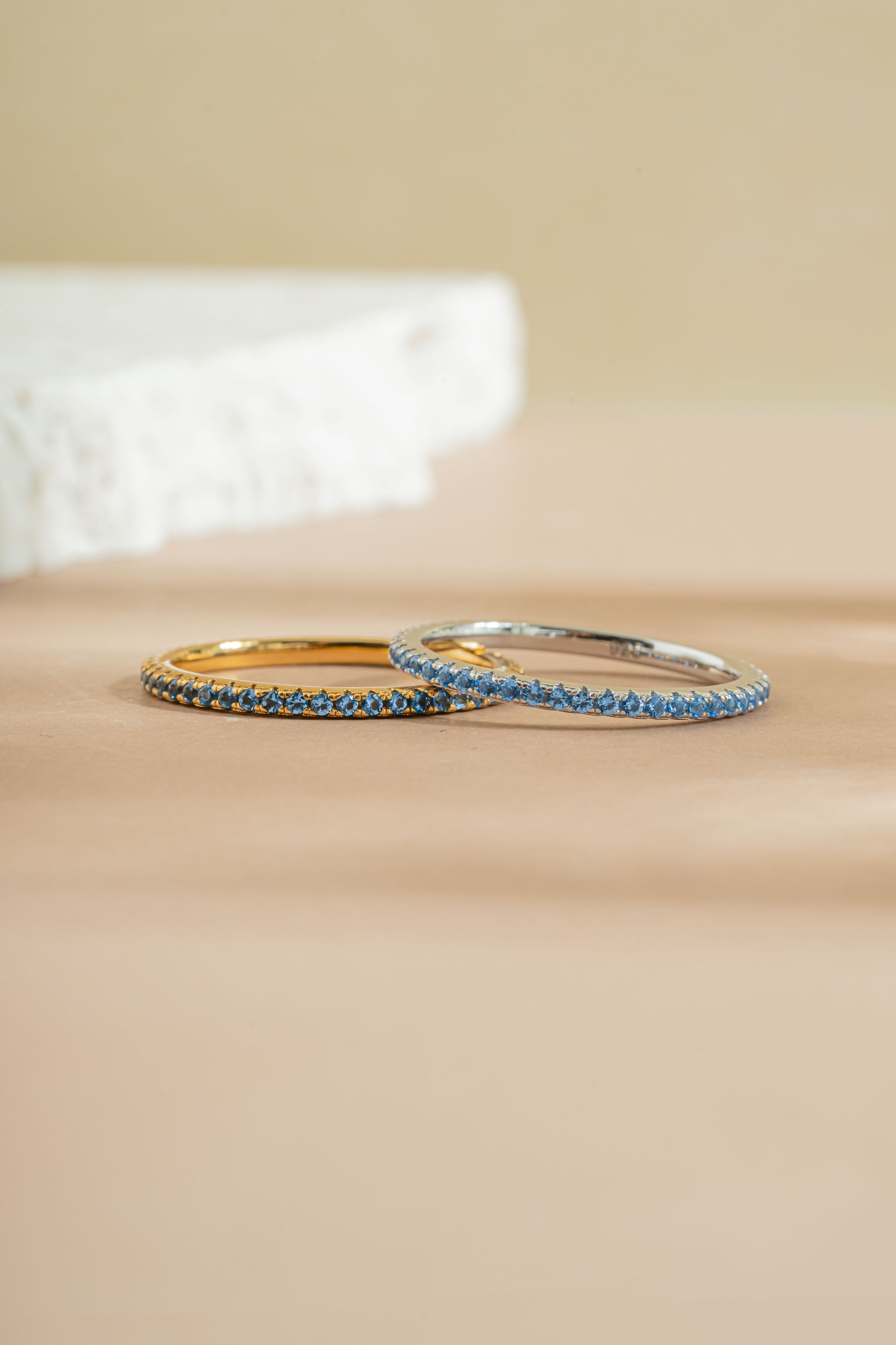 gold and sterling silver blue topaz eternity ring band neutral background 