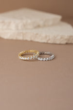 gold studded eternity ring and sterling silver studded eternity ring neutral background