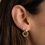model wearing gold knot hoops mixed with dainty studs for a chic contrast.