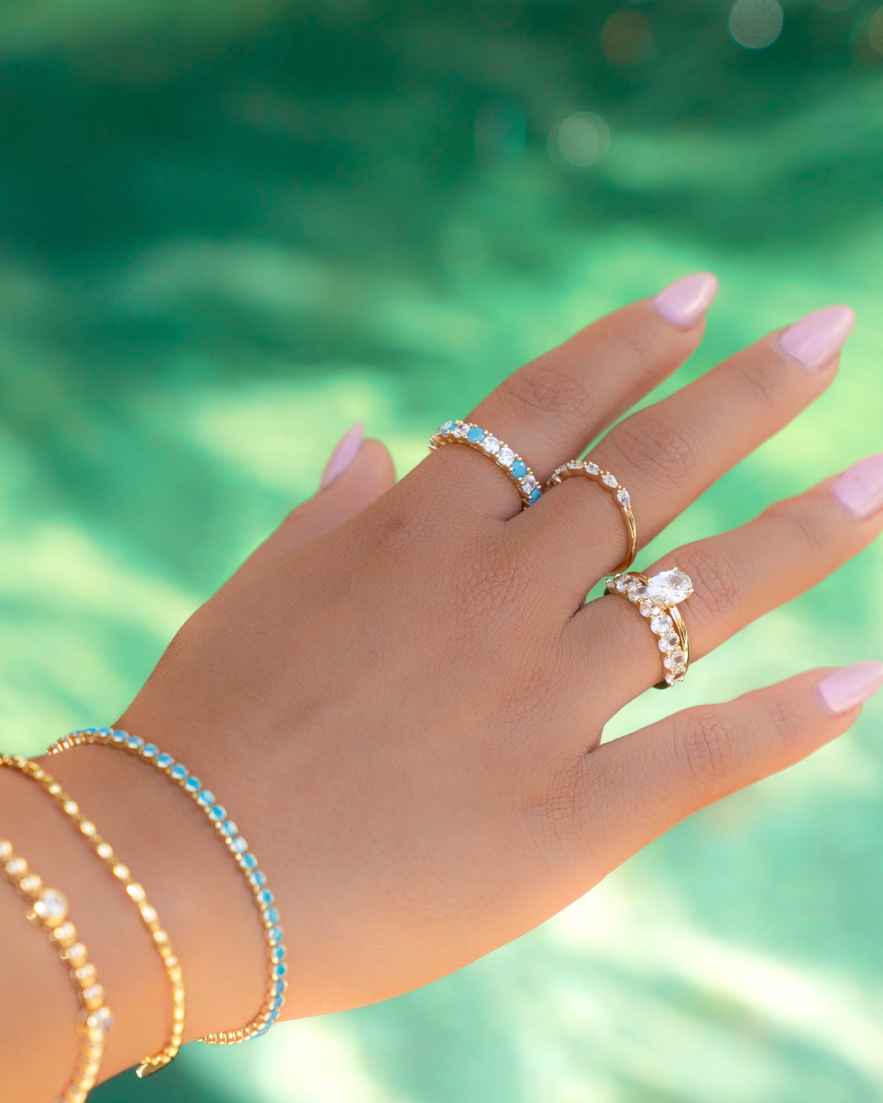 gold turquoise and diamond eternity ring on models hand stacked with gold and turquoise jewelry
