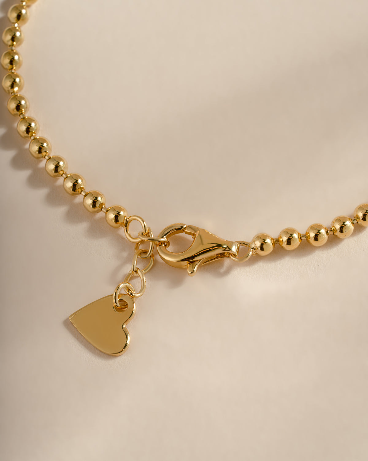 Close-up of the graduated bracelet's lobster clasp, extension chain and heart-shaped end tag.