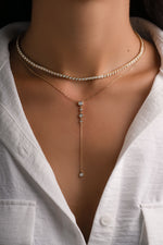 Gold square tennis necklace layered with a lariat necklace, stylish Sami Jewels jewelry piece for elegant accessorizing.