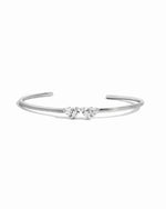 Flat lay of a silver cuff bracelet with heart and teardrop gemstones. 
