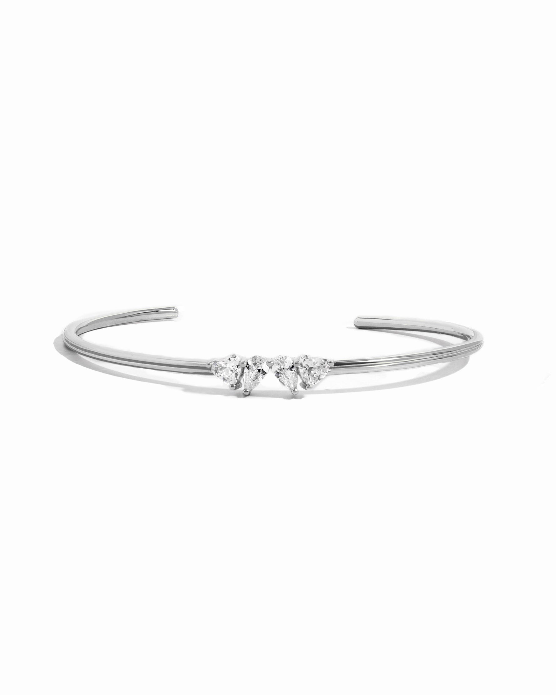 Flat lay of a silver cuff bracelet with heart and teardrop gemstones. 