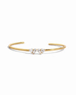 A close up of gold cuff bracelet with the Toi et Moi heart and pear gemstones. 