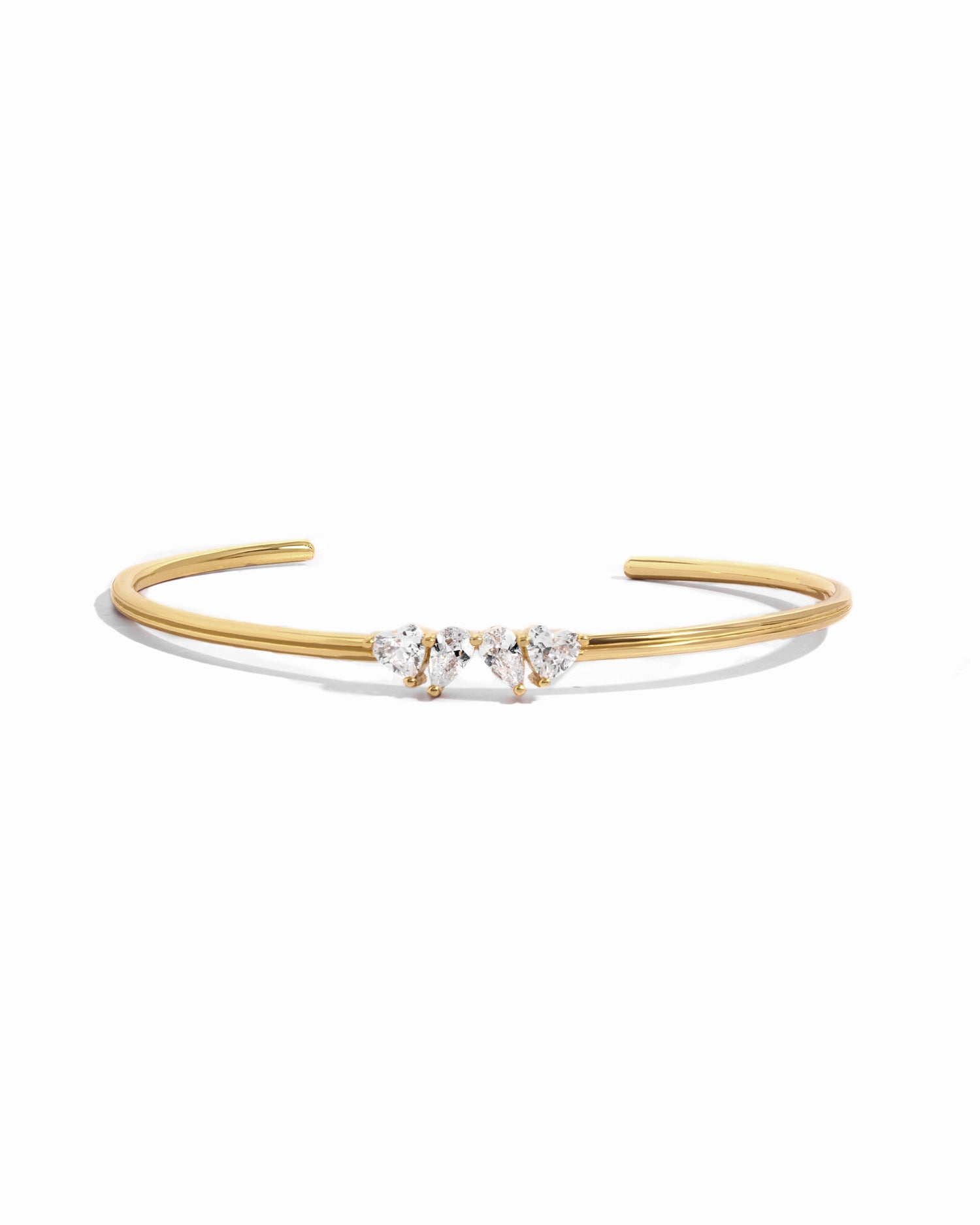 A close up of gold cuff bracelet with the Toi et Moi heart and pear gemstones. 