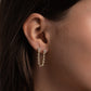 model wearing two-piercing gold dangle earrings linked by a fine tennis chain studded with diamonds.