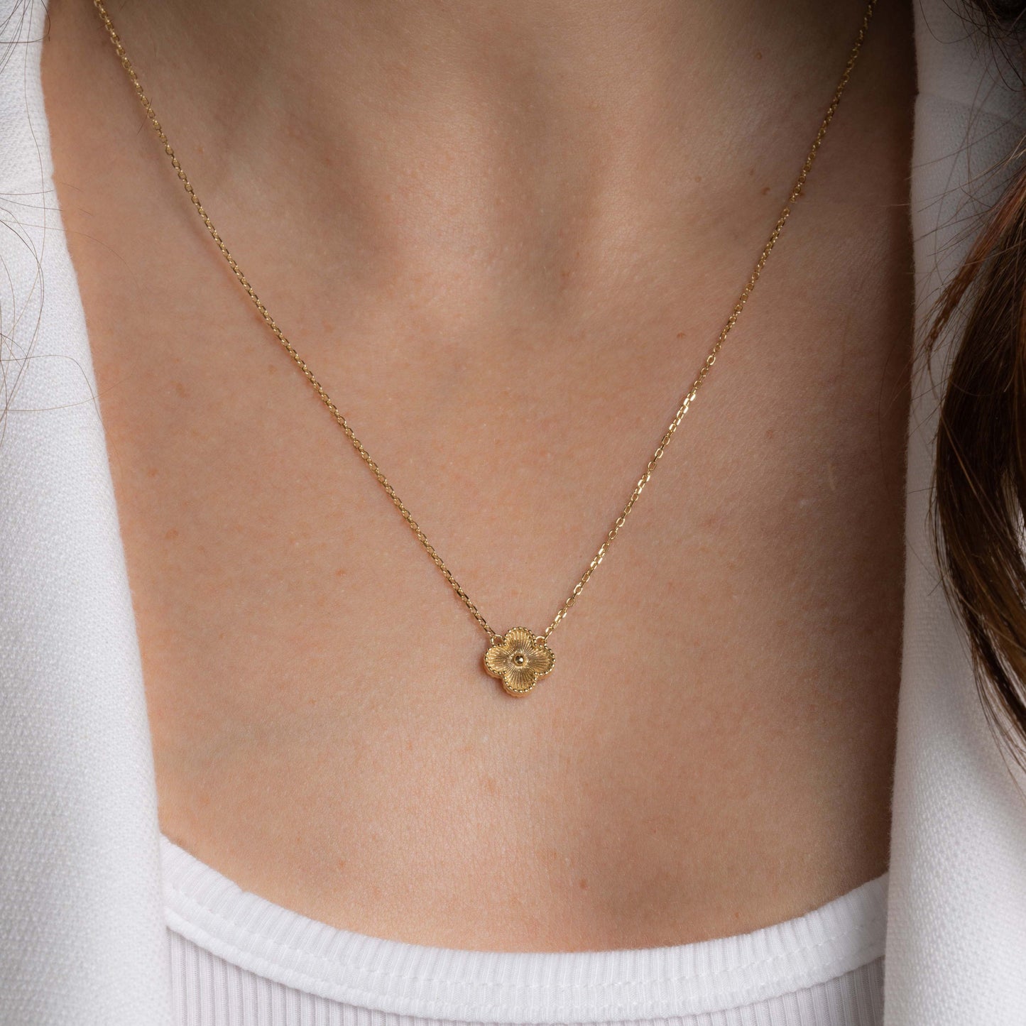 Model wearing a gold chain necklace with four leaf clover intricate design.