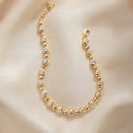 Flat lay of gold beaded bracelet with tennis chain design.