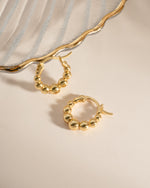 Close-up of Sami Jewels graduated beaded gold hoop earrings, featuring detailed beaded design and shiny finish.