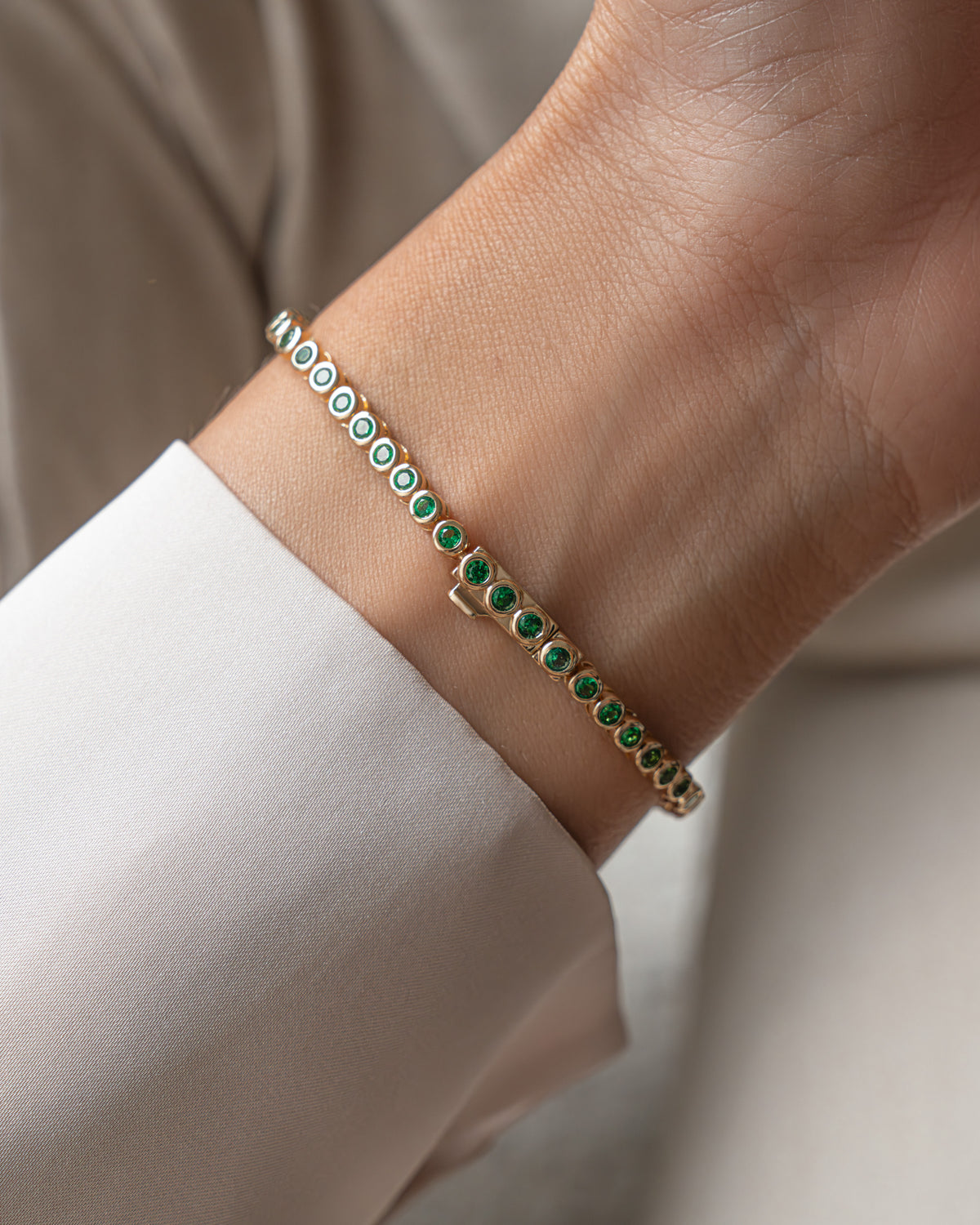 Close view of green stone bezel bracelet on a model's wrist