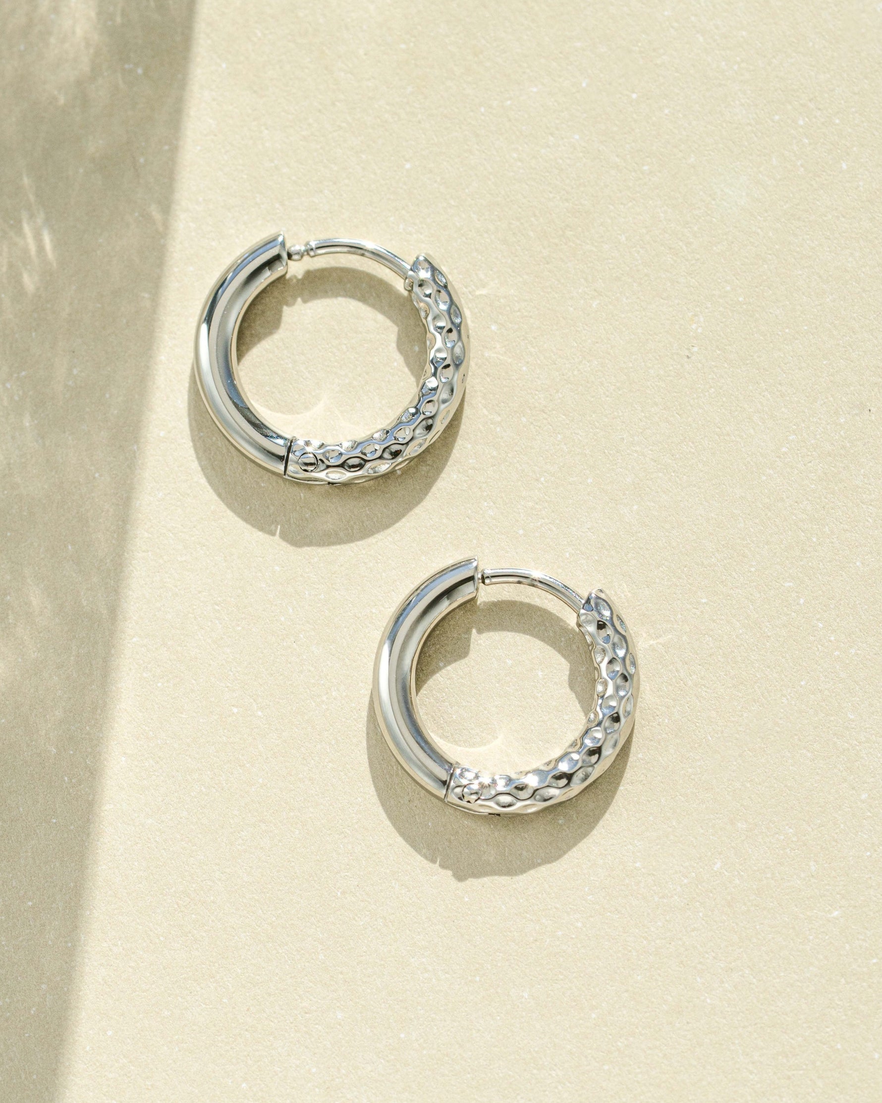 Silver stainless steel half-textured huggie hoop earrings by Sami Jewels, showing close-up of sleek, modern jewelry design.