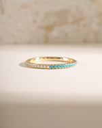Close-up of Sami Jewels turquoise and diamond eternity ring with gold band, showcasing intricate design and sparkling gemstones.