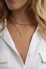 Gold halo emerald cut necklace on Cuban chain, worn by a model, showcasing elegant jewelry design by Sami Jewels.