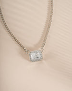 Close-up of Sami Jewels halo emerald cut necklace on a sterling silver Cuban chain, showcasing its elegant design.