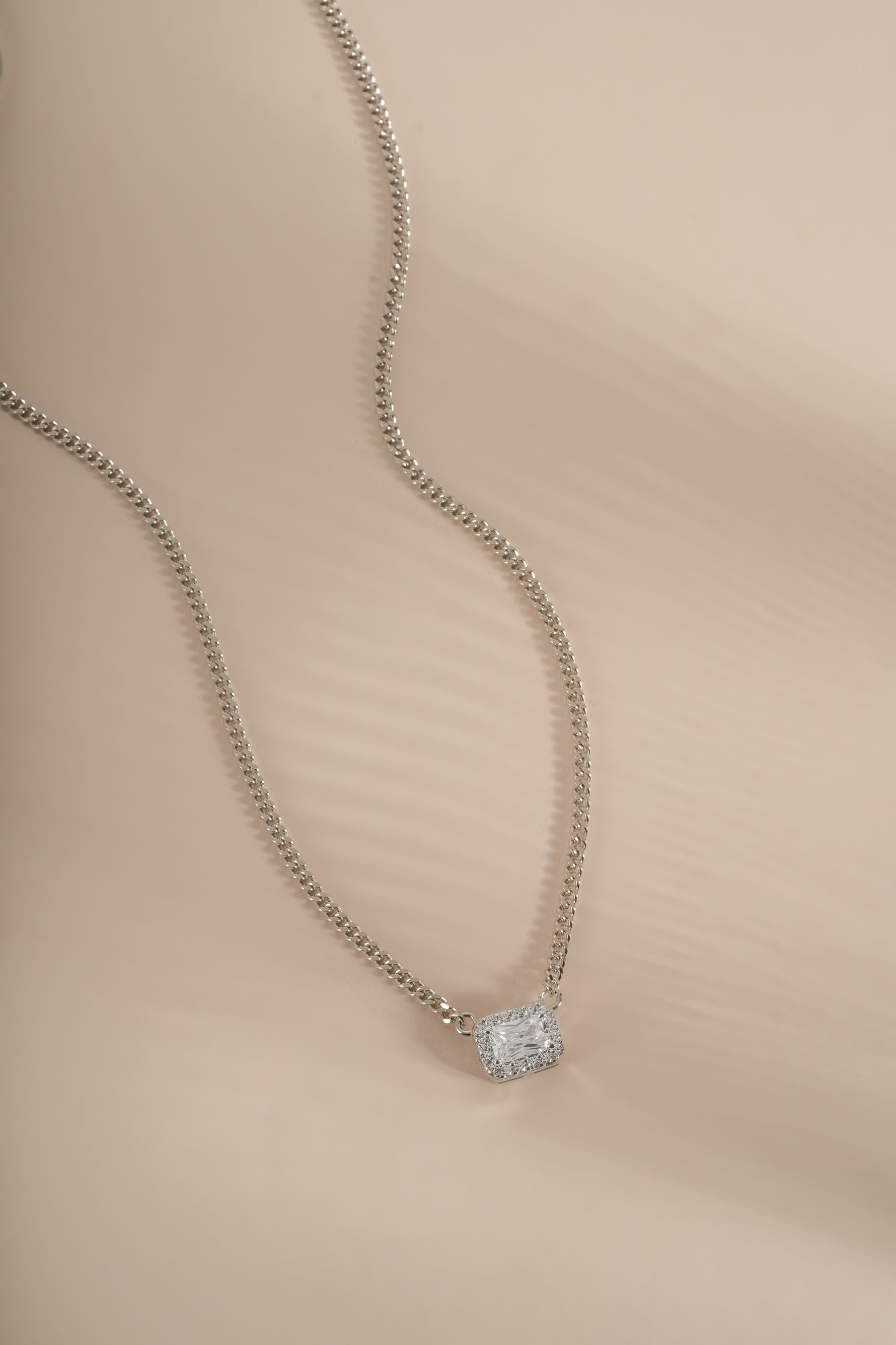 Sterling silver halo emerald cut necklace on a Cuban chain, featuring a sparkling center gemstone and intricate chain design