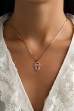 Rose gold Hamsa necklace from Sami Jewels featuring intricate design, displayed on a model.