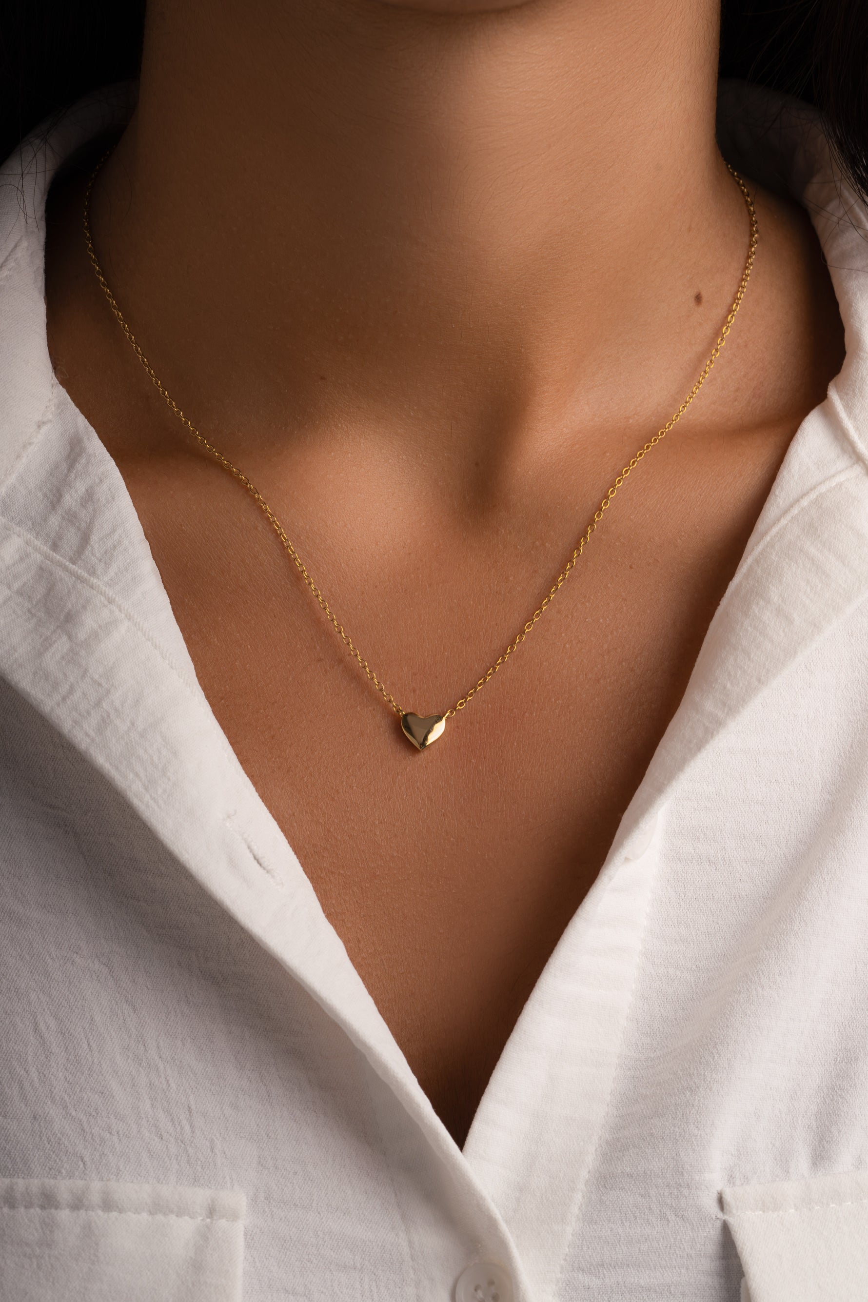 Gold heart necklace from Sami Jewels, featuring a delicate pendant on a fine chain worn by a model.