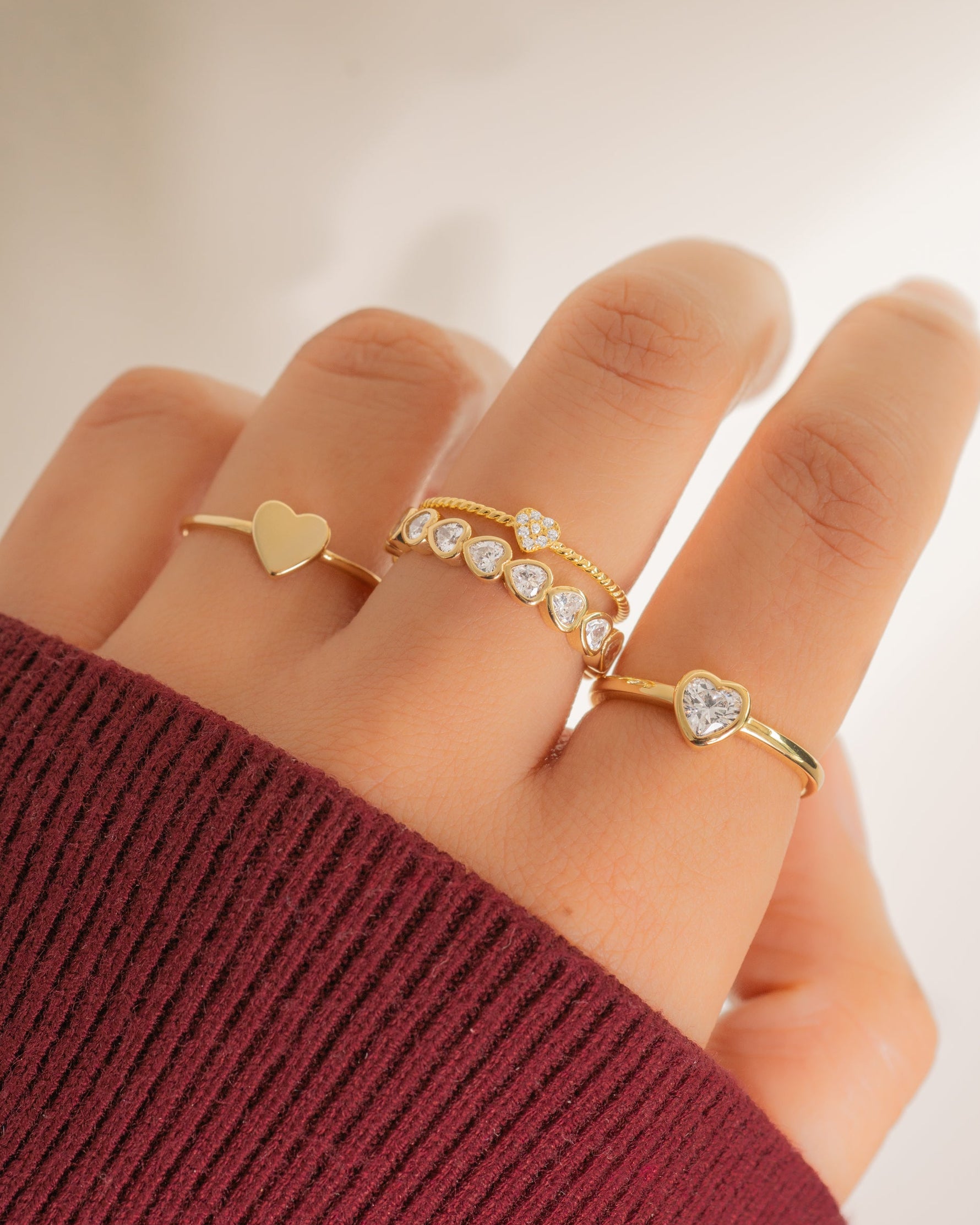 Gold Valentina Heart Ring from Sami Jewels stacked on a model's finger, showcasing a delicate heart-shaped design.