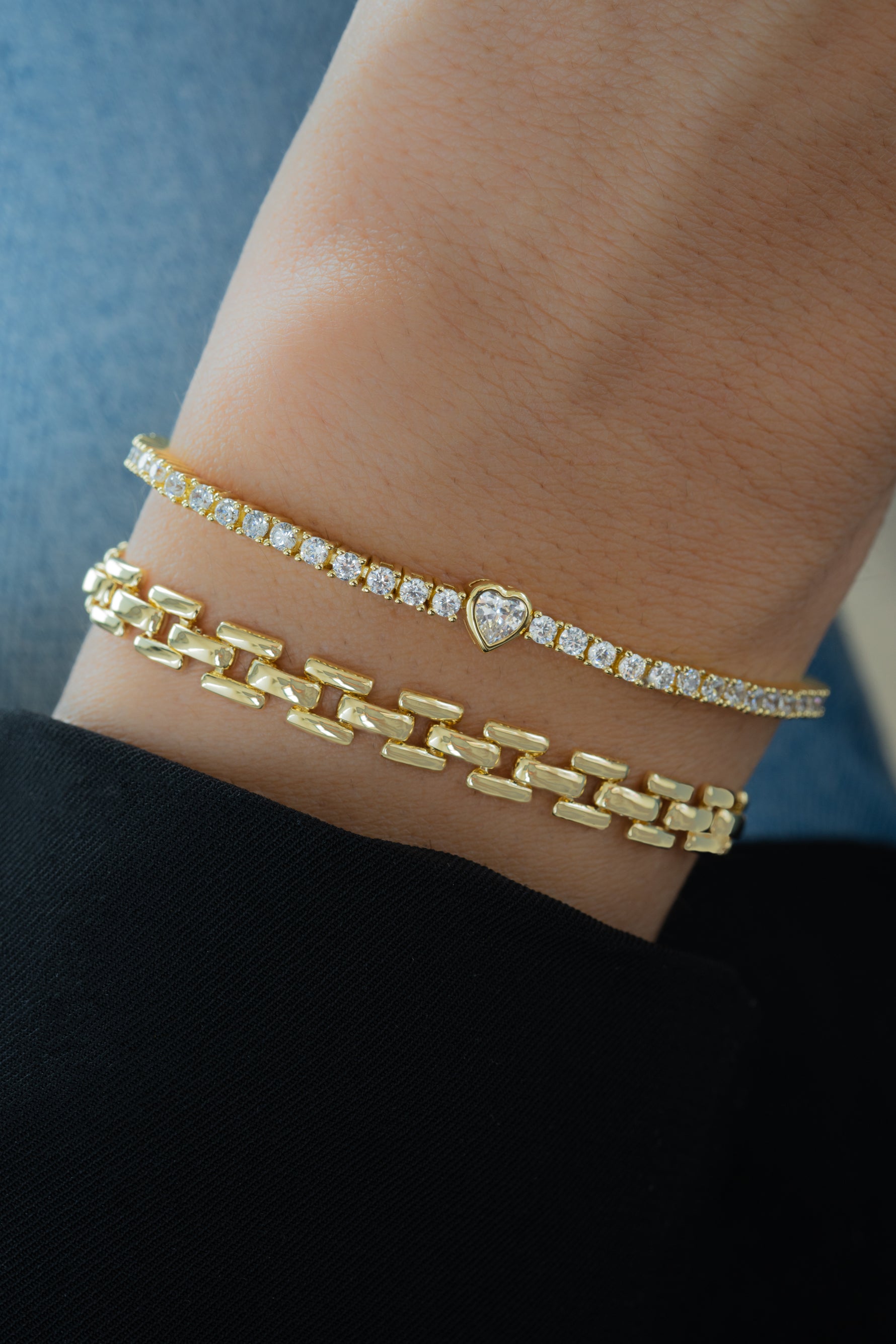 gold heart tennis bracelet paired with a gold link bracelet
