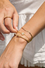 Sami Jewels 2mm herringbone bracelet stacked on wrist, showcasing sleek gold design and fine textured pattern.