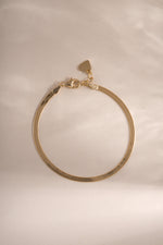 Gold 2mm Herringbone bracelet by Sami Jewels, showcasing its sleek, flat chain design laid out on a neutral background.