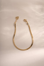 Gold 2mm herringbone bracelet from Sami Jewels with lobster clasp closure, showcasing a sleek, woven chain design.