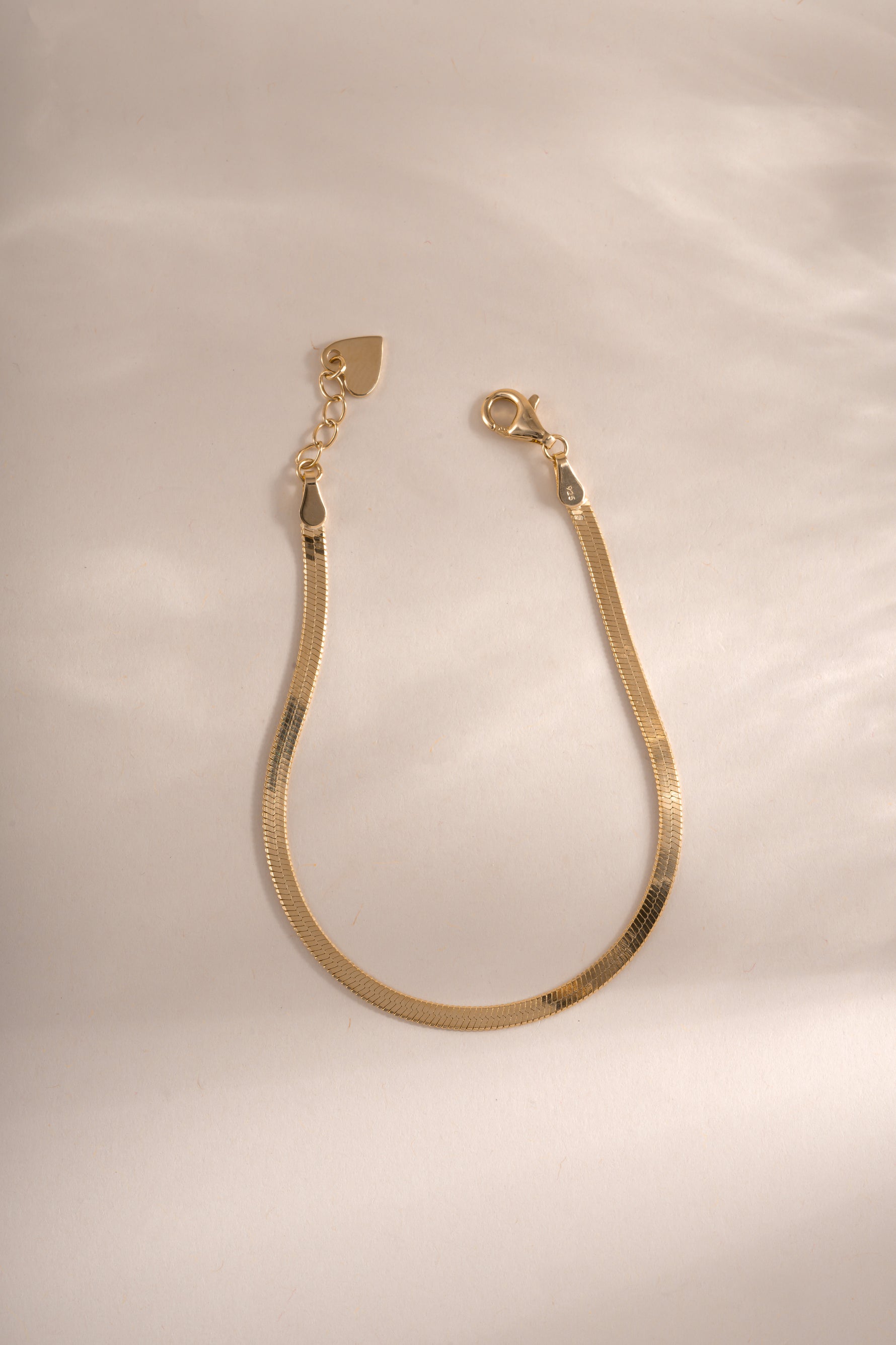 Gold 2mm herringbone bracelet from Sami Jewels with lobster clasp closure, showcasing a sleek, woven chain design.