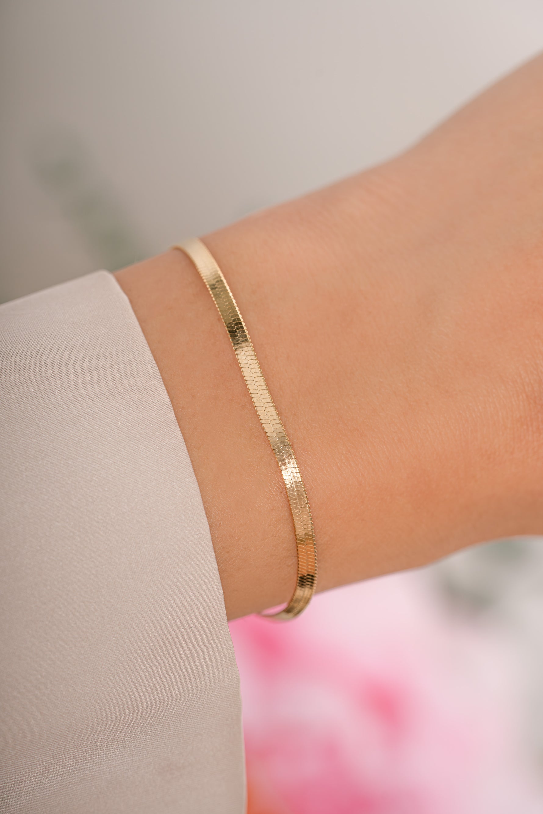 Gold 2mm herringbone bracelet by Sami Jewels, featuring a sleek, woven chain design worn on a model's wrist.