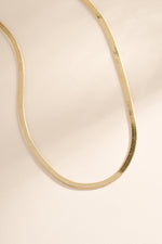 Close-up of a 2mm gold herringbone chain necklace by Sami Jewels showing its smooth, flat woven design.