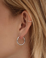Silver stainless steel hinged tube hoop earrings by Sami Jewels, showcasing sleek, waterproof design on a model.