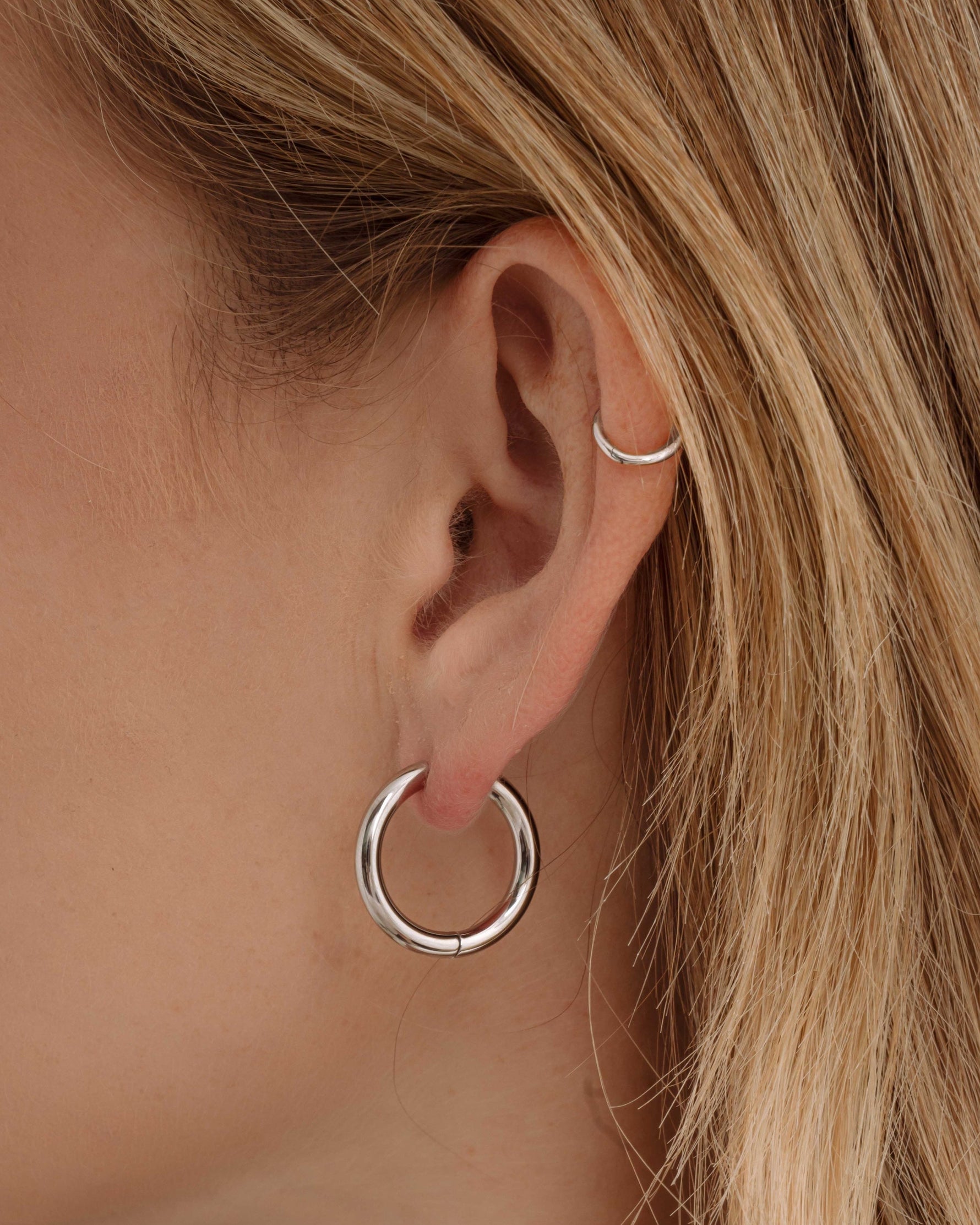 Silver stainless steel hinged tube hoop earrings by Sami Jewels, showcasing sleek, waterproof design on a model.