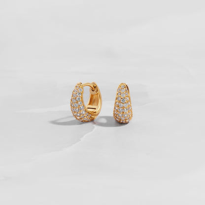 Hinged huggie hoop earrings plated in 14k gold on white background