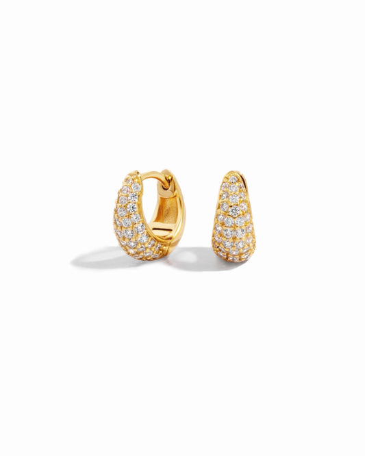 Hinged huggie hoop earrings plated in 14k gold on white background