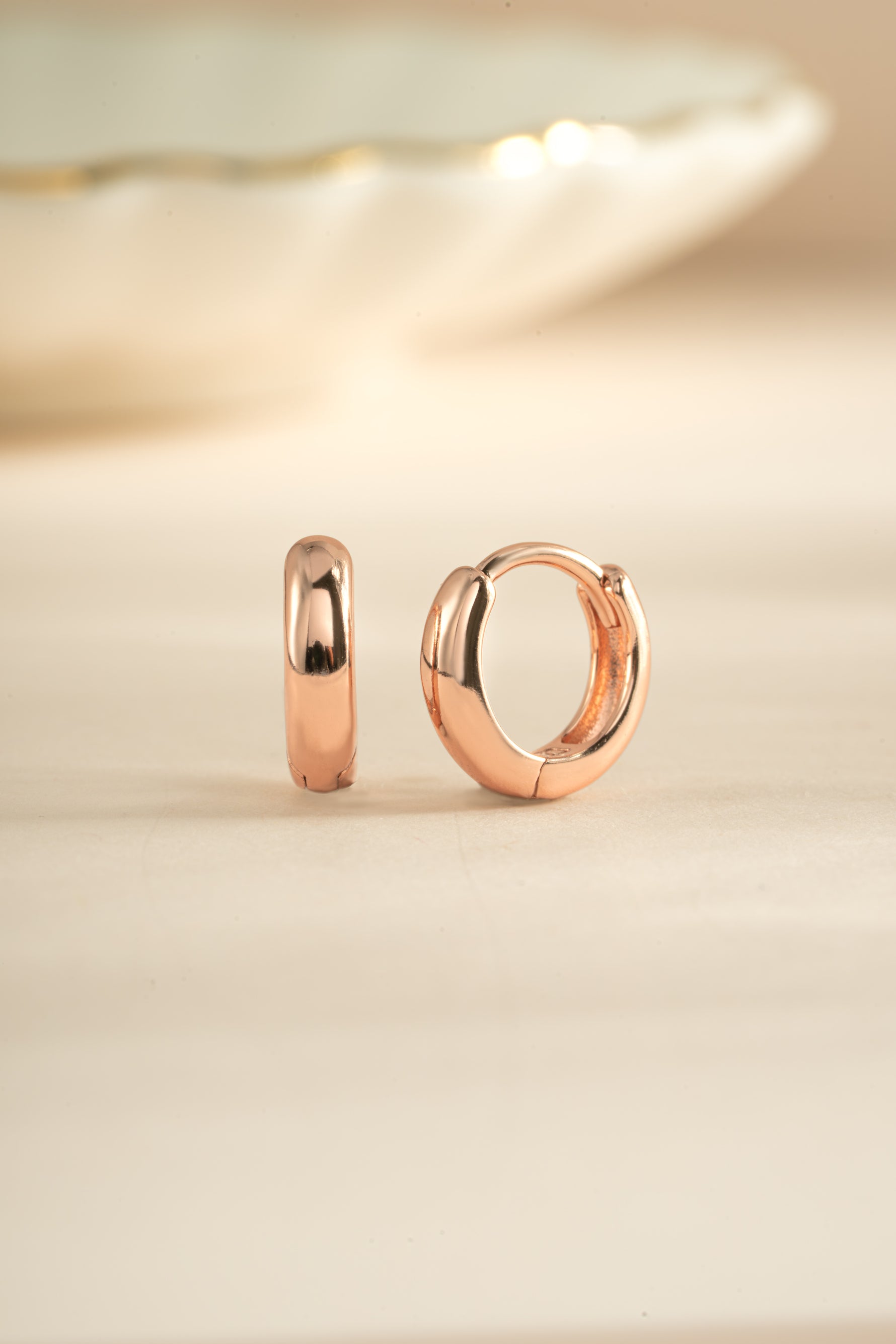 Rose gold minimalist huggie hoop earrings by Sami Jewels, close-up of small, sleek hoop earrings on a white background.