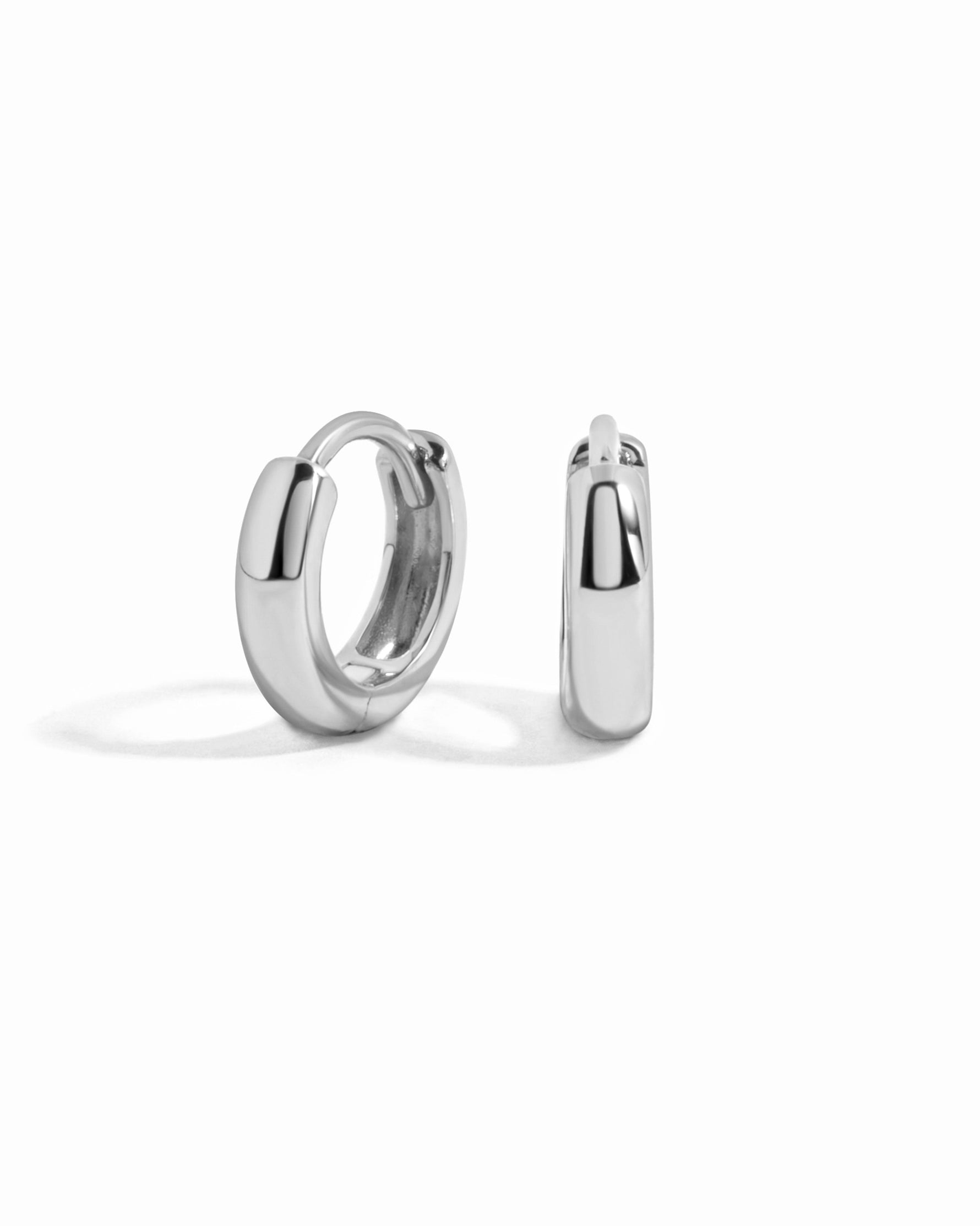 Sterling silver minimalist huggie earrings by Sami Jewels on a white background. Small, sleek hoop earrings with a modern design.