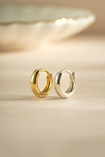 Gold and sterling silver minimalist huggie hoop earrings by Sami Jewels, showcasing sleek, small round hoop design.