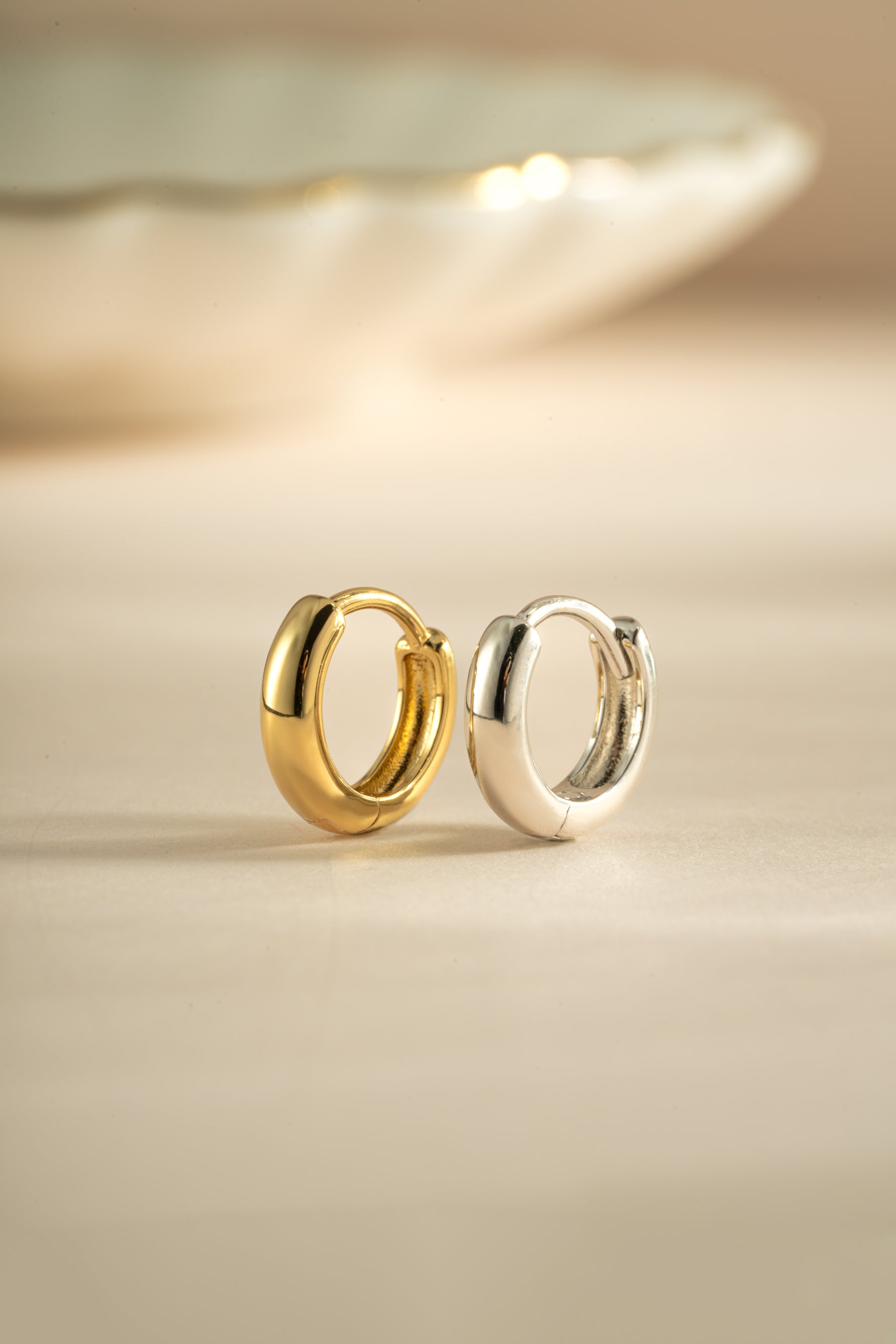 Gold and sterling silver minimalist huggie hoop earrings by Sami Jewels, showcasing sleek, small round hoop design.