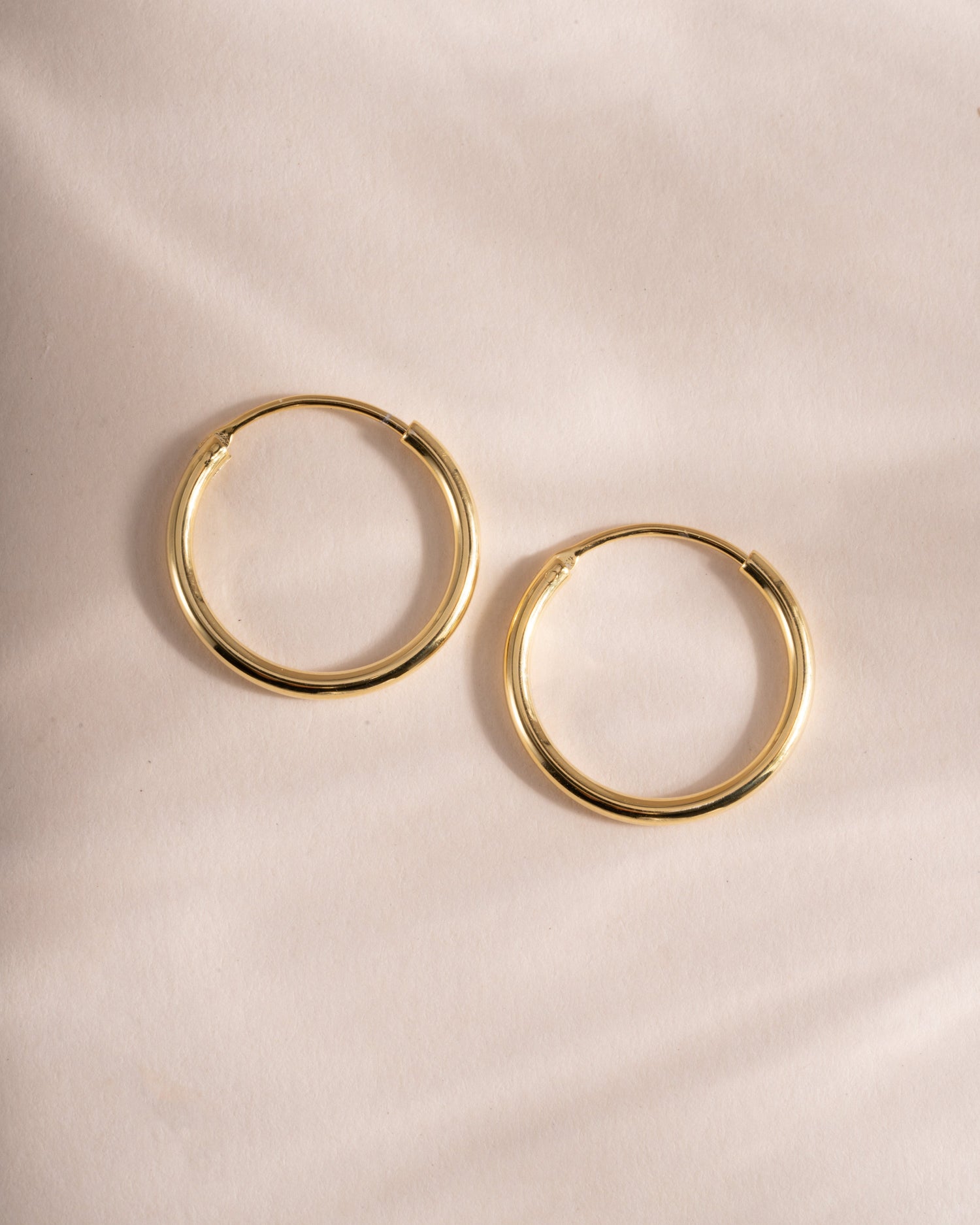 infinity hoop earrings in gold, 13mm on a simple background