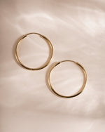 Gold 32mm infinity hoop earrings by Sami Jewels, showcasing sleek, circular jewelry with a polished finish.