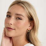 model wearing minimalist gold knot hoops layered with diamond studs for subtle sparkle.