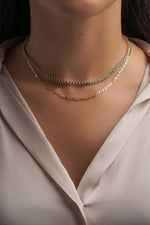 Gold mariner chain necklace layered with an emerald tennis necklace