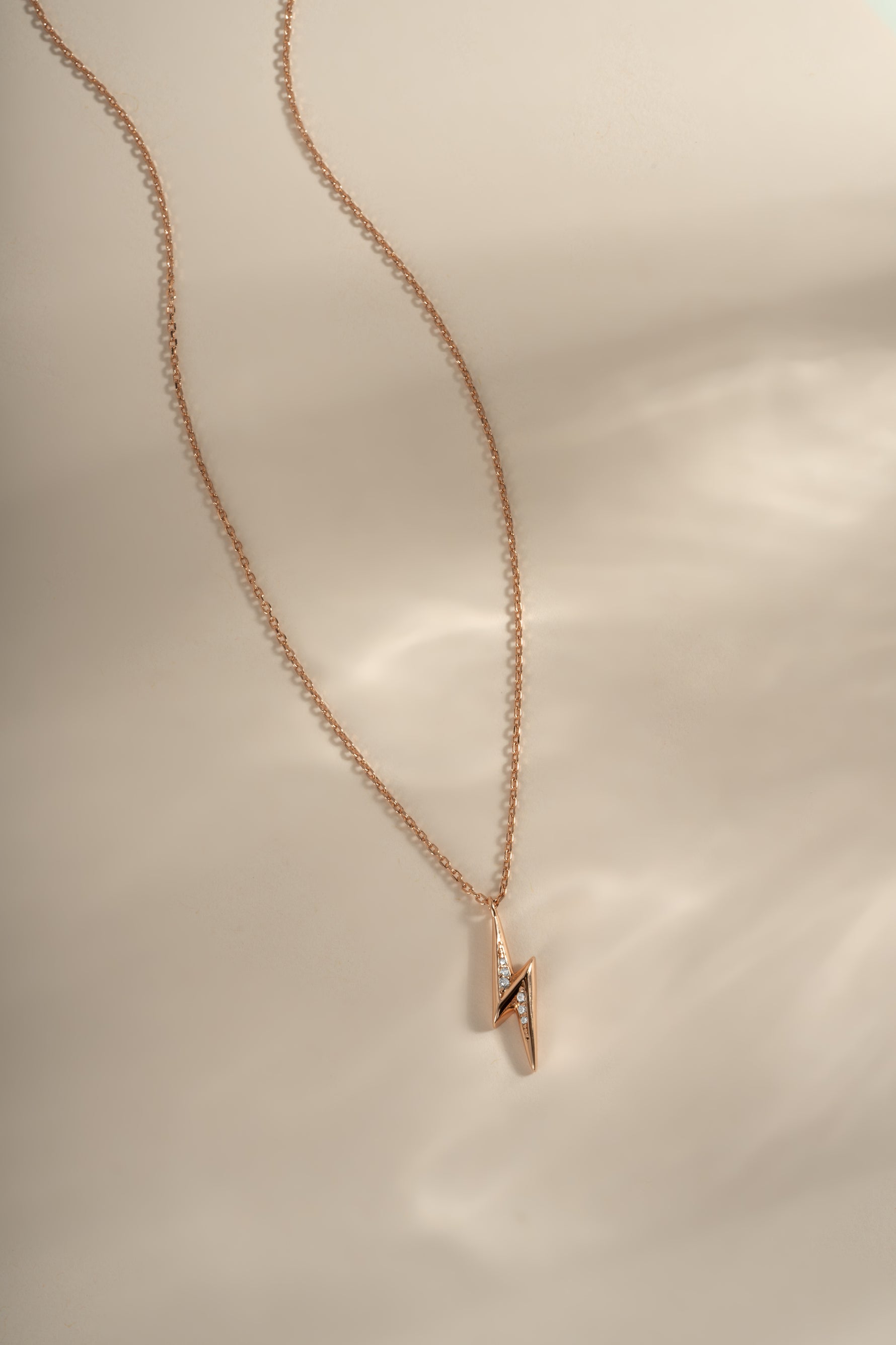Rose gold lightning bolt necklace from Sami Jewels, showcasing a sleek, modern jewelry piece on a chain.
