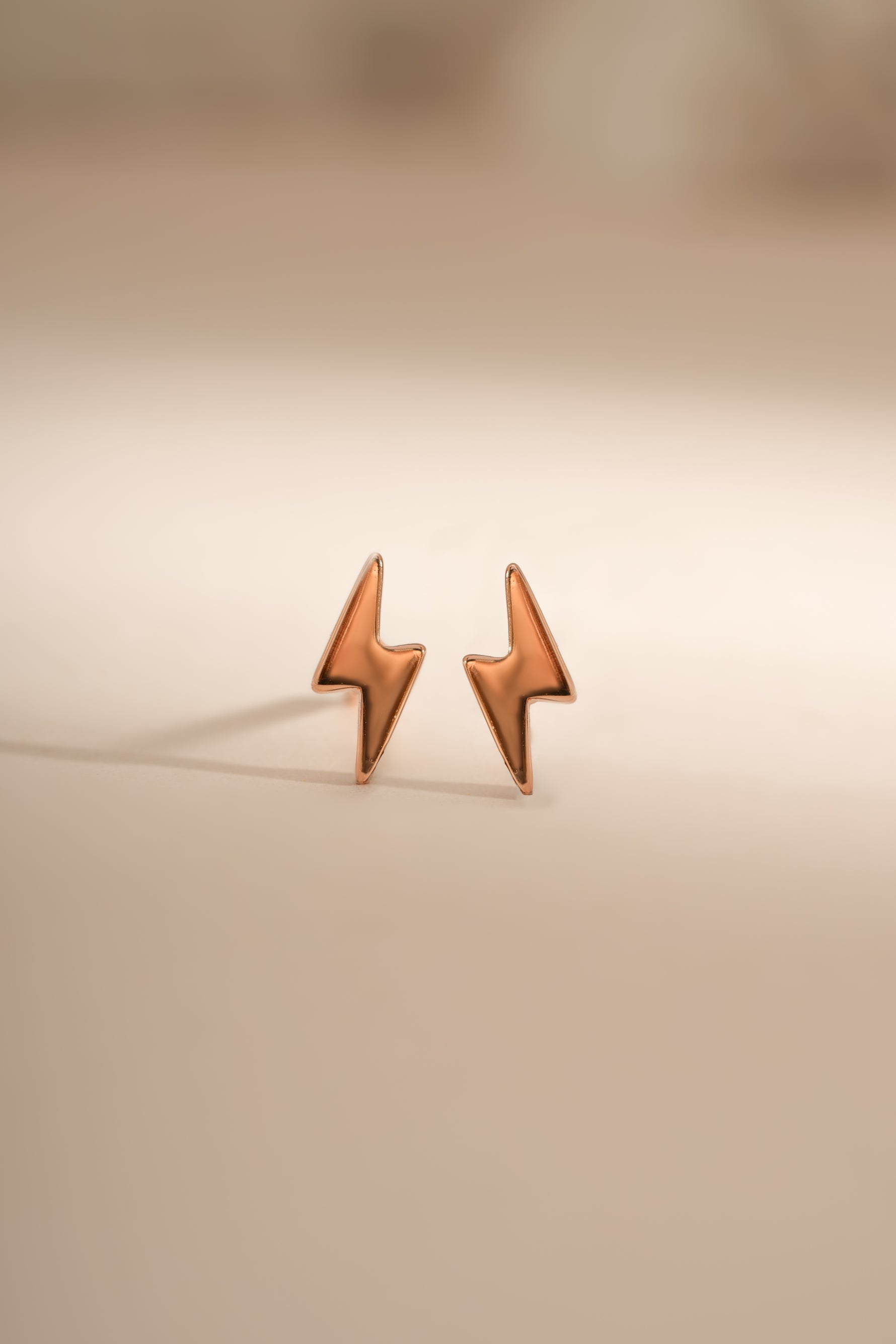 Rose gold lightning bolt stud earrings by Sami Jewels, featuring sleek, modern lightning bolt design in a close-up shot.