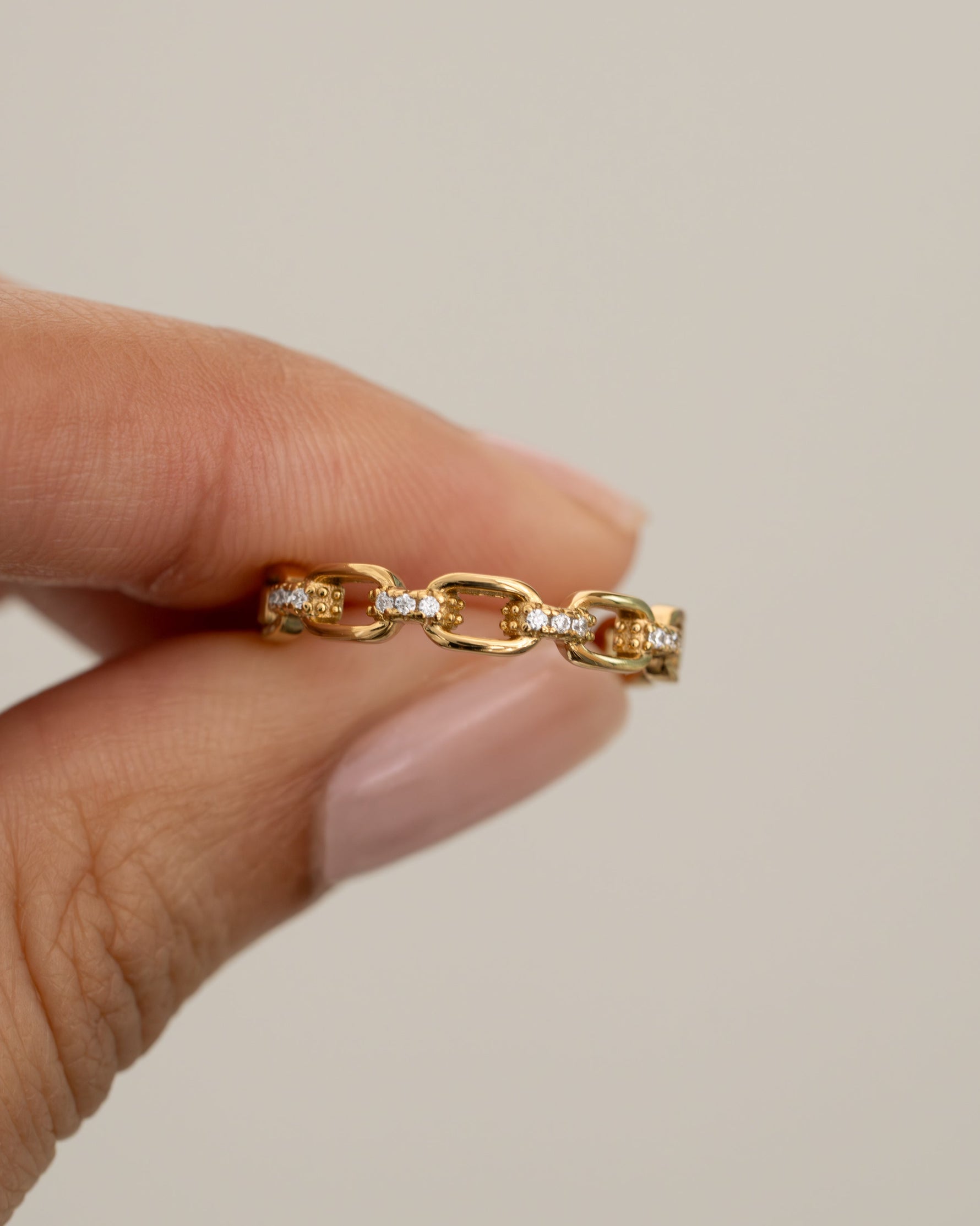 link chain ring in gold held between two fingers