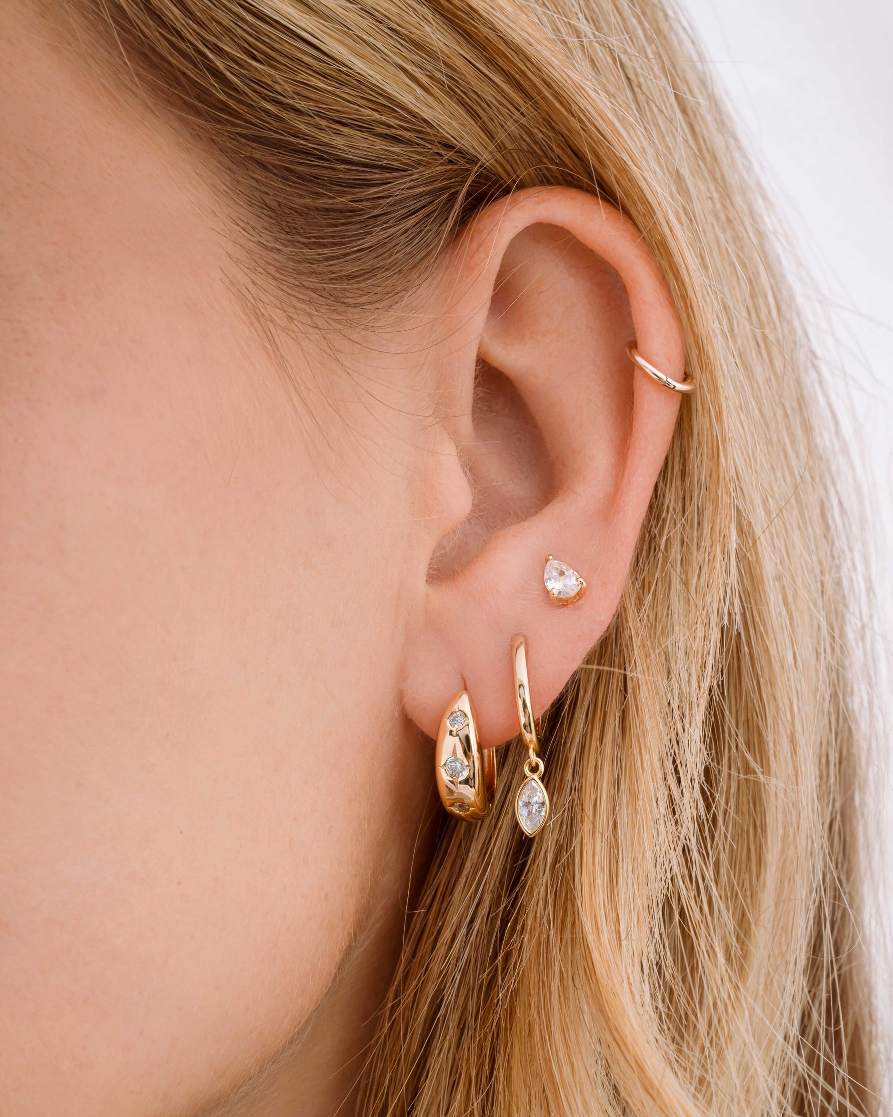 Gold Sami Jewels Marquise Bezel Drop Huggie earrings stacked on ear, featuring marquise-shaped bezels and hoop design.